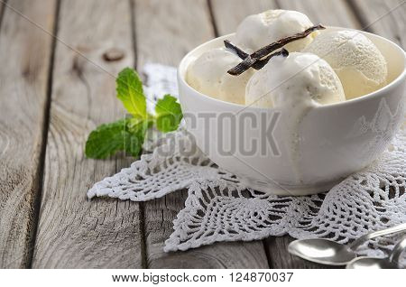 Vanilla ice cream in white bowl on rustic wooden background