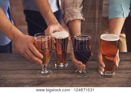Male group holding glasses of dark and light beer at the table