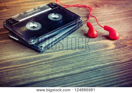 Audio cassette tapes and red earphones over wooden table vintage style selective focus