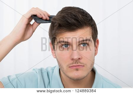 Close-up Of Young Man Combing His Hair With Comb
