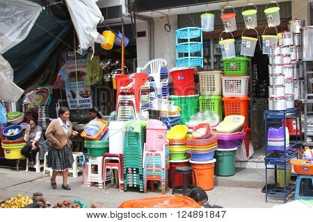 CAJAMARCA PERU - APRIL 1 2016: Street scene in Cajamarca Peru on April 1 2016. Small store selling lots of plastic ware with Peruvian farm woman walking in front of it.