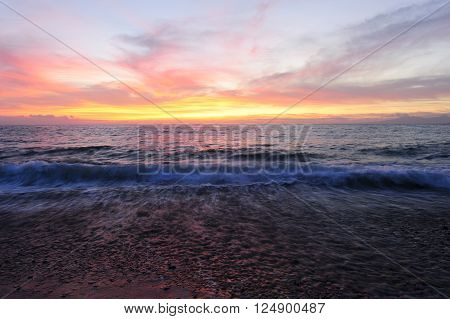 Ocean sunset is brightly lightred and golden seascape with a gentle wave rolling to the shore.
** Note: Shallow depth of field