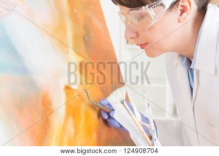 Artwork conservator at work with old painting wearing protective suit