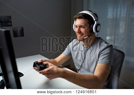 technology, gaming, entertainment, let's play and people concept - happy young man in headset with controller gamepad playing computer game at home and streaming playthrough or walkthrough video