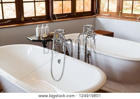sanitary, plumbing and washing concept - close up of bathroom with two bathtubs