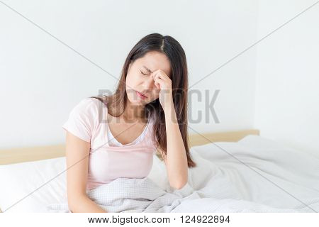Woman suffer from headahce and sitting on bed