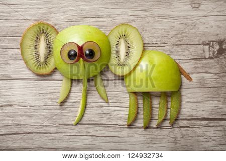 Elephant made of apple and kiwi on wooden desk