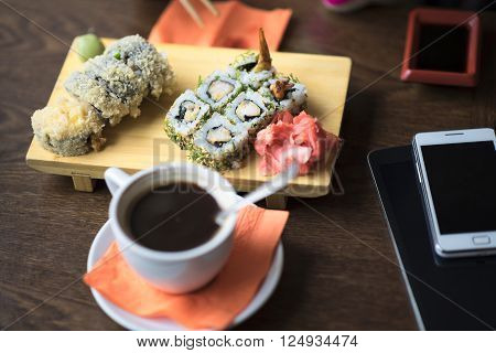 Photo of the table with an evening dinner or lunch rolls close-up on the table is to persist cup of coffee or tea in a cafe, lies next tablet and phone