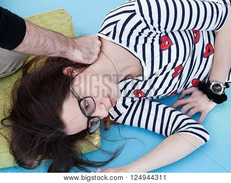 Reflexology. Man's hand presses woman's neck by the knuckles woman lays on the mat
** Note: Soft Focus at 100%, best at smaller sizes