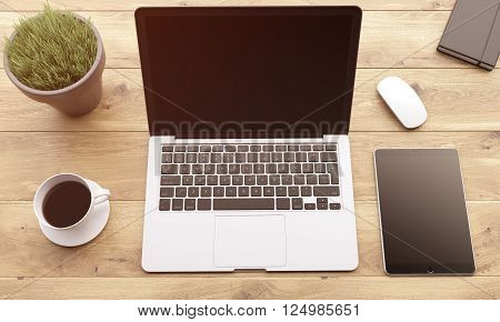 Laptop smartphone and tablet with black screens coffee plant mouse and datebook on wooden table. Concept of workplace. Mock up. 3D rendering