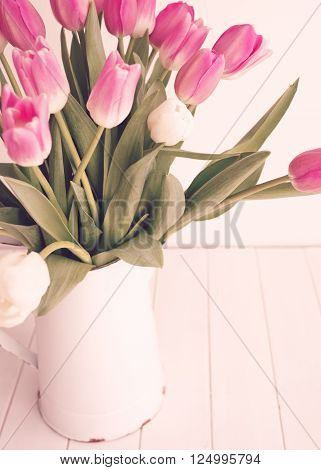 Pink and white tulips inside a white tin vase soft focus