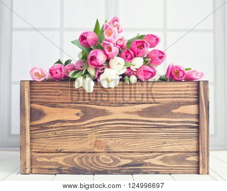 Pink and white tulips over a wood crate