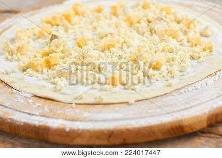 Close up chopped cheese on pizza crust. Chopped and diced cheese, close up. Cheese pizza cooking.