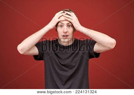 Handsome man shocked by the mistakes made in the process, a lot of hard work. Keeps hands on her head and laments from the ensuing problems.