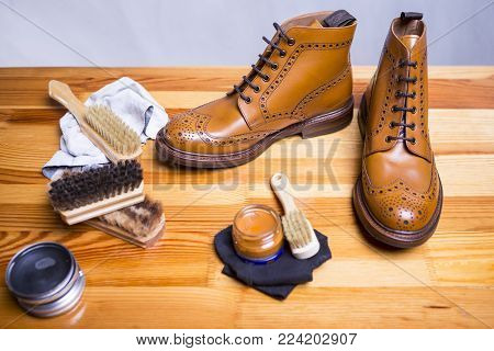 Footwear Concepts.Closeup of Premium Tan Brogue Boots Along with Cleaning Accessories and Cleaning Cloth.Horizontal Image
