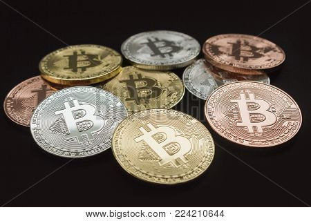 Bit coins with gold, silver, copper colored on black background.