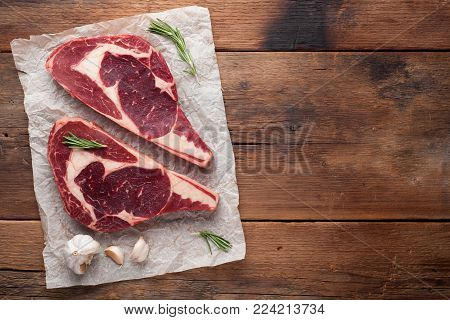 Two fresh raw marble meat, black Angus ribeye steak with spices on a old rustic table. Raw beef on a wooden background. Top view with copy space.