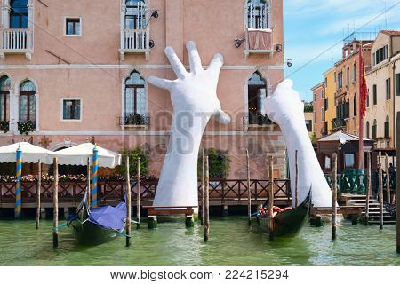 VENICE,ITALY - JULY 26,2017 : Giant hands supporting an old palace next to the Grand Canal, a work of art by Lorenzo Quinn