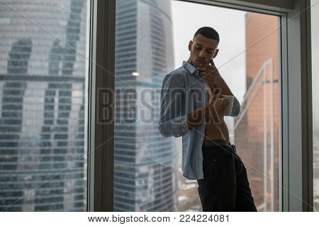 A businessman drinks a morning coffee before the work. Panoramic windows background.