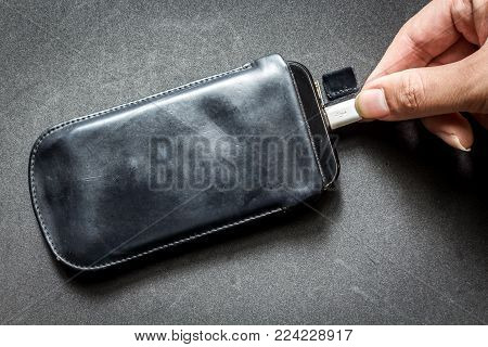 Hand Hold Smartphone With Charger On Black Background