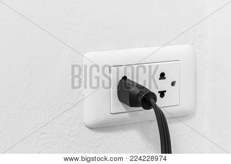 Black Cable Plugged In A White Electric Outlet On Whith Wall