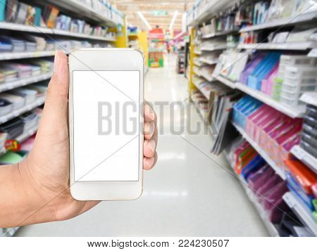 Hand Holding Mobile Smart Phone On Office Supply Shelf In Store Blur Background