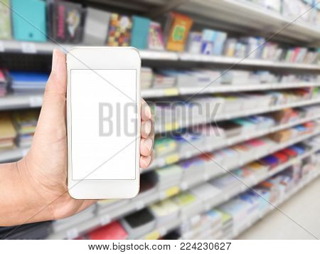 Hand Holding Mobile Smart Phone On  Bookshelf In Book Store Blur Background