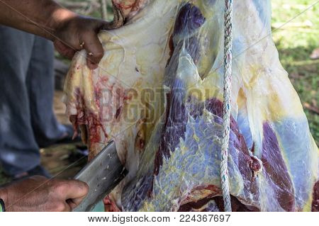 Closeup of butcher's hand cutting meat with knife in the local market called Tamu in Keningau,Sabah,Malaysia.Its a place where all farmers,fishermen & vendors gathers weekly to sell their products.