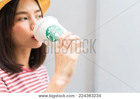 Bangkok, Thailand - January 30, 2018 : Woman drinking Starbucks coffee on the home, Starbucks brand is one of the leaders in coffee service worldwide.