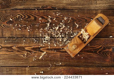 old planer and shavings on dark wooden table, top view