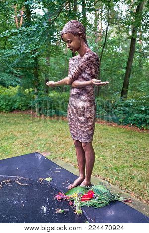 DRESDEN, GERMANY - SEPTEMBER 8, 2017: A statue of the Grieving Girl in the cemetery Heidefriedhof. The sculpture depicts a girl in a simple dress, her arms crossed over her chest so that the whole figure forms a cross.