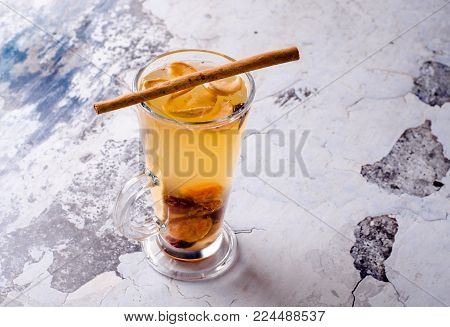 Hot grog with lemon, cinnamom stick and honey on a gray background, selective focus. Fruit drink with tea, rome, anise and other spices. Food and drink concept, view from above.