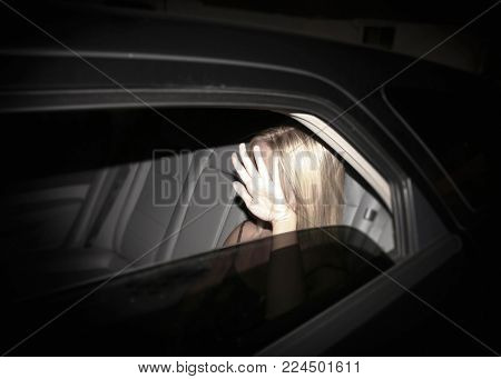 Paparazzi concept - invasion of privacy - young starlet blonde woman blocking her face while being photographed in a black limousine 