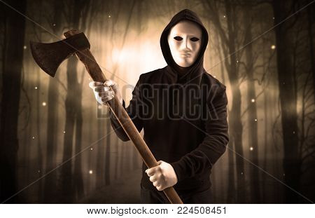 Masked armed hitman in dark thick forest with foggy mysterious concept