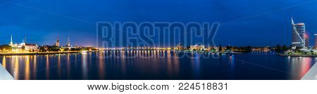 Riga, Latvia - July 01, 2016: The Panoramic Cityscape In Evening Illumination On Both Sides Of The Daugava, Western Dvina River. Night View Of Stone Bridge Afar. Central Building  Swedbank
