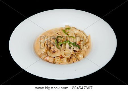 Talifele with chicken and mushrooms in a white plate on a black background.