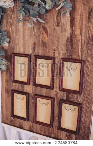 Wooden board with frames in brown baguette, decorated with flowers on an easel. Moke up.