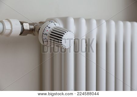 heating temperature controller on white radiator in the apartment