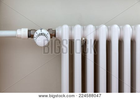 heating temperature controller on white radiator in the apartment