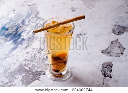 Hot grog with lemon, cinnamom stick and honey on a gray background, selective focus. Fruit drink with tea, rome, anise and other spices. Food and drink concept, view from above.