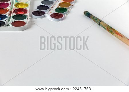 children's paints and a brush on white paper