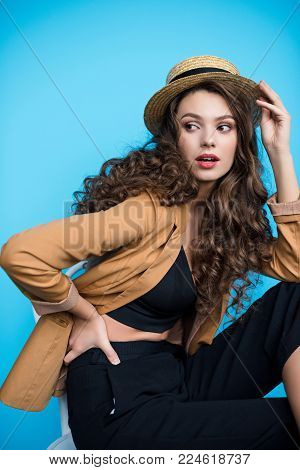 beautiful young woman in stylish canotier hat and jacket looking away