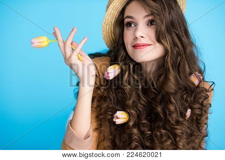 smiling young woman in canotier hat with flowers in her long curly hair