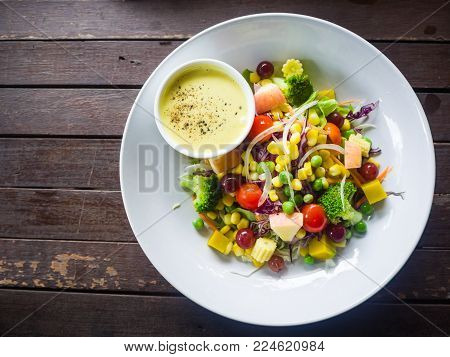 salad and salad dressing cream,mix vegetable in white plate on wooden table.