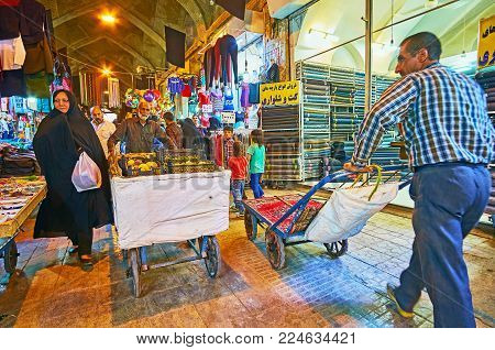 SHIRAZ, IRAN - OCTOBER 12, 2017: The busy alley of Vakil Bazaar, this place is  always crowded - clients, porters with carts, street vendors with different goods go in both directions, on October 12 in Shiraz.