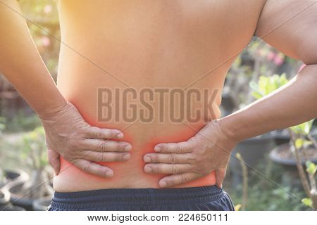 Man with hands holding his waist back in pain. A man pain concept with red spot.