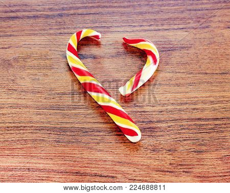 candy in the shape of heart on a wooden background for the celebration of Valentine's Day. Heart is broken. Cheating.