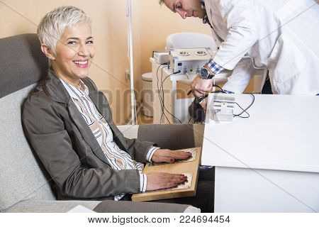 Senior woman checking her health status at the clinic, undergoing quantum and bioresonant medical exam