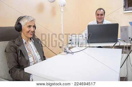 Senior woman checking her health status at the clinic, undergoing quantum and bioresonant medical exam