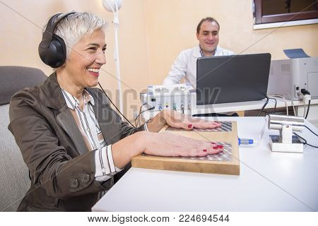 Senior woman checking her health status at the clinic, undergoing quantum and bioresonant medical exam